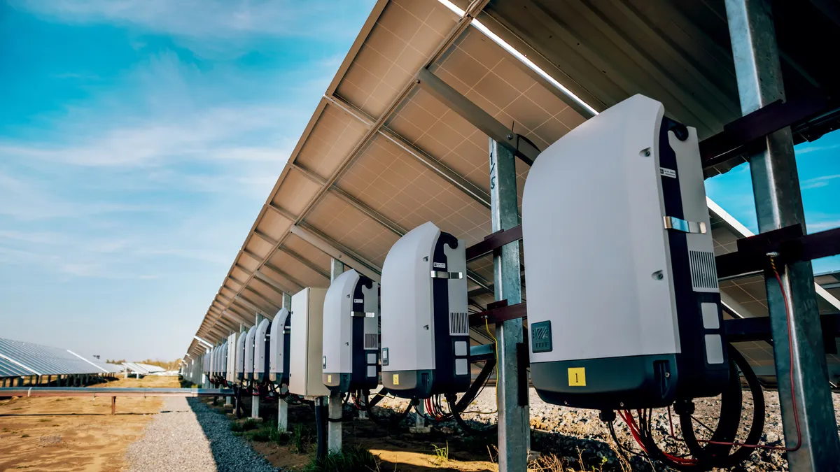 A row of solar inverters behind a solar panel.