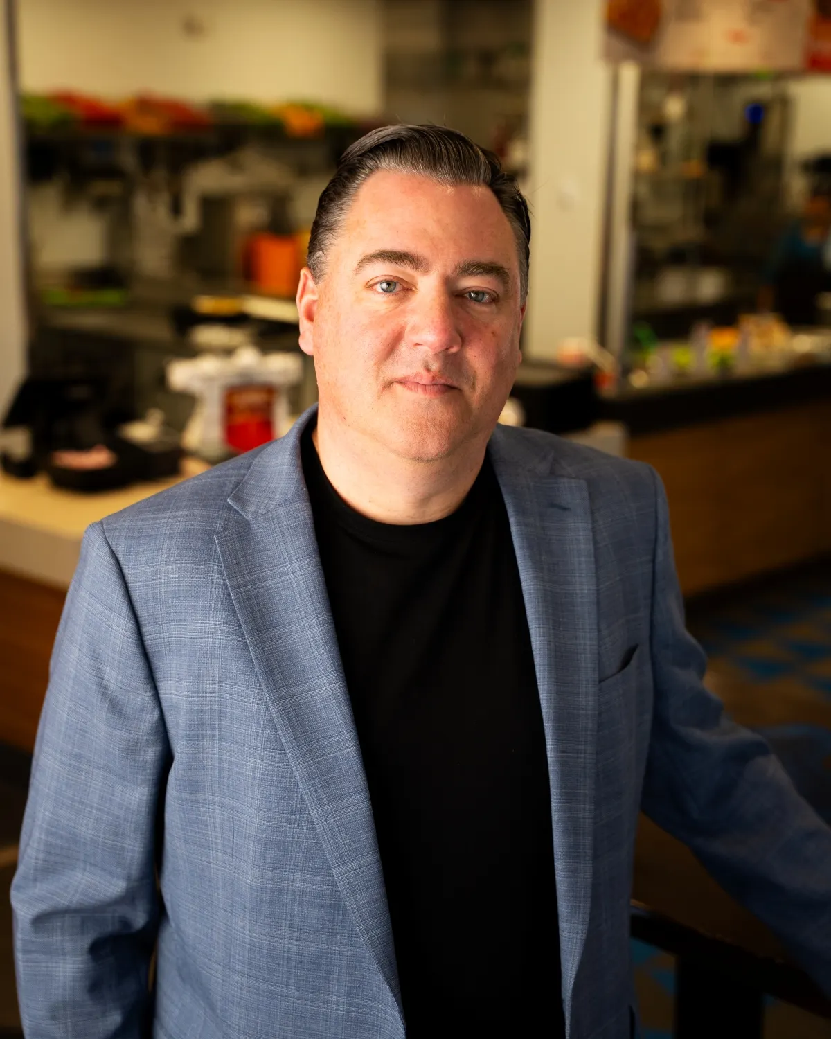 Mike Burns, Cafe Rio's new CEO, stands before the camera in a checked sport coat.