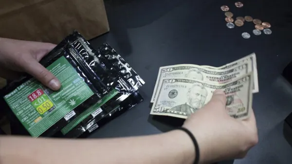 An employee collects money while holding packages of marijuana