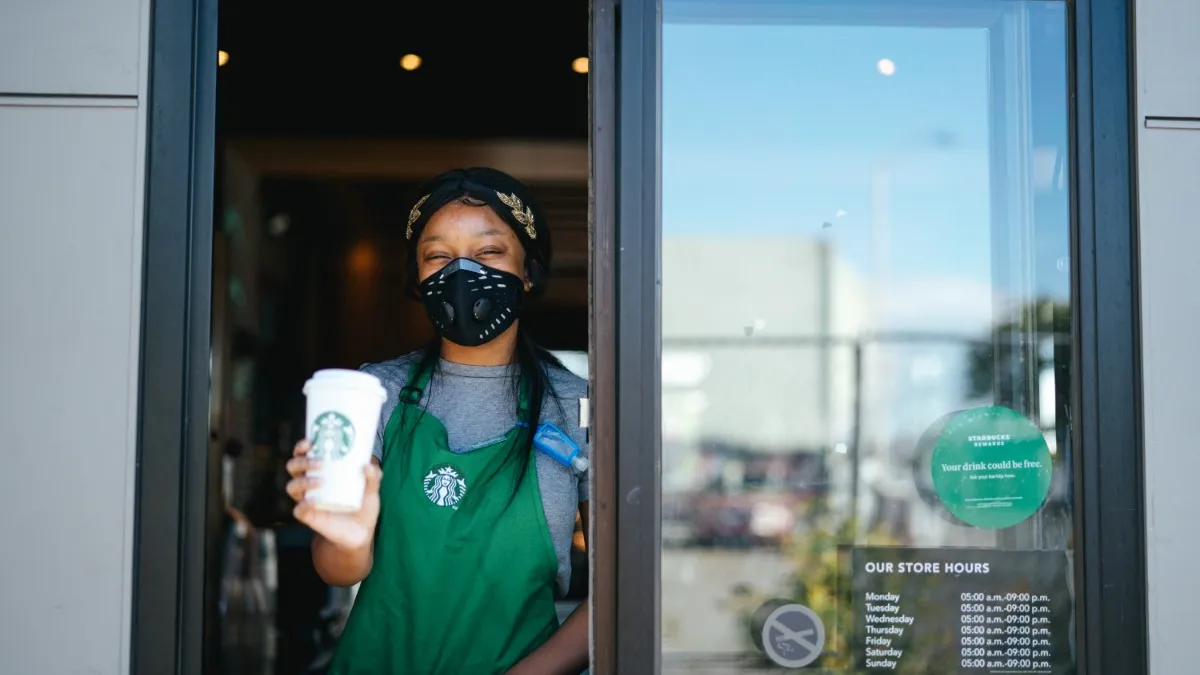 Starbucks employee at a drive-thru wearing a mask