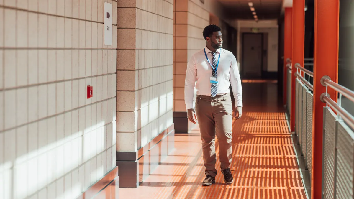 A teacher looks to the side while walking down a school hallway.