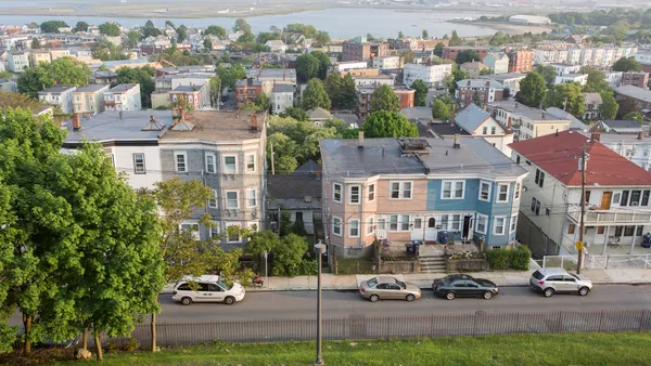 Aerial image of multifamily buildings lining the streets. Behind the homes is a large body of water.