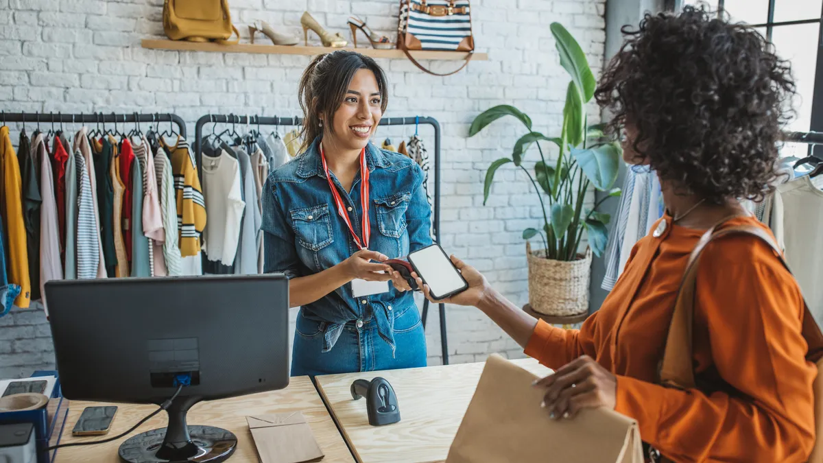 A woman making a purchase at a store using her cell phone to pay.