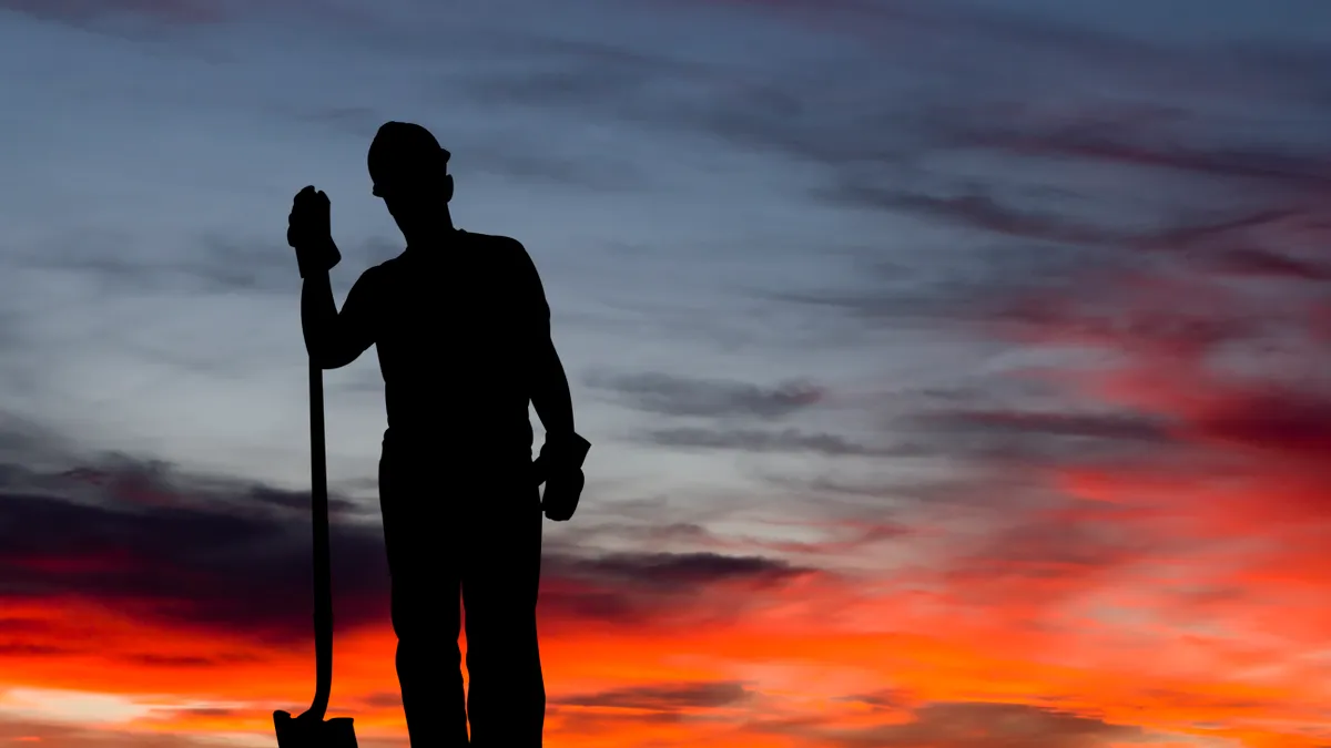 A lone construction worker pauses on a jobsite.