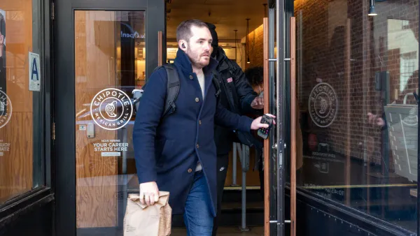 An image of a man leaving a Chipotle. He is holding a brown bag.