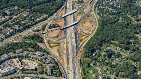 An aerial image of a set of large highways that overlap and loop around each other, surrounded by trees.