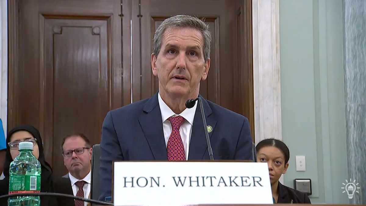 A person in a blue suit speaking into a microphone.