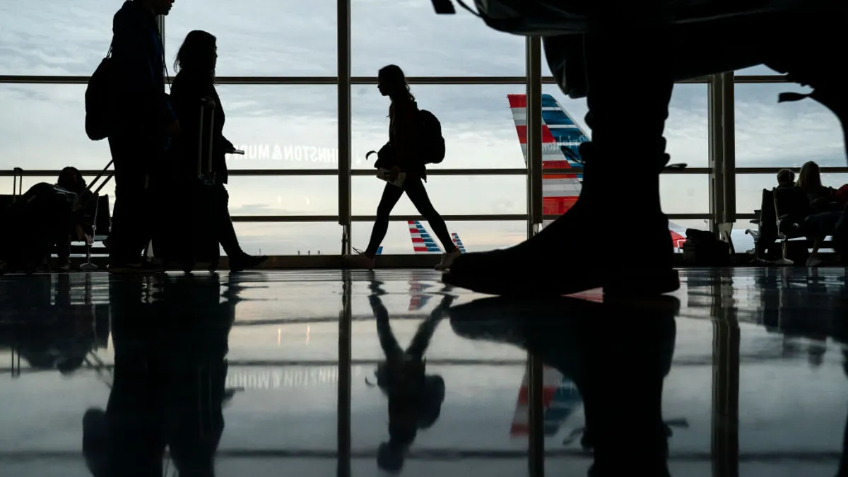 Silhouettes of travelers are seen in an airport terminal.