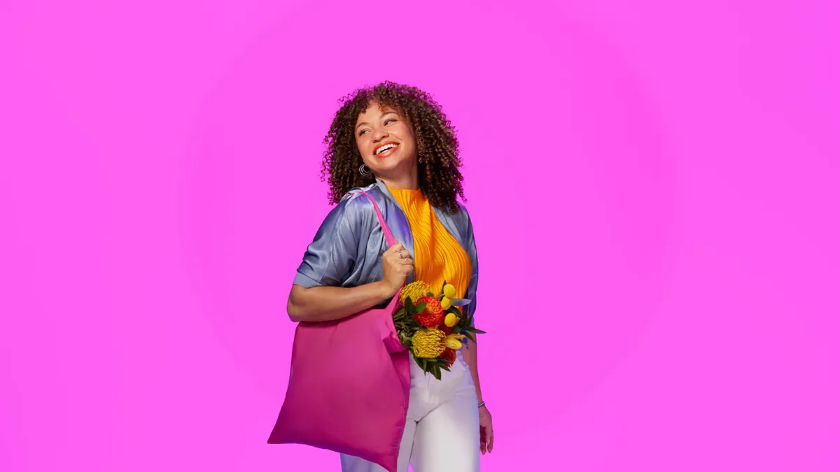 Woman with a tote bag in front of a pink background