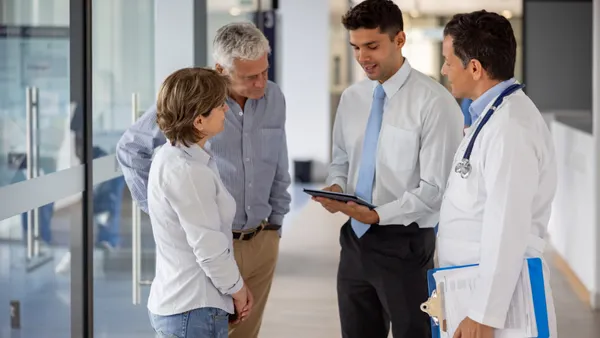 Medical professional looking at a tbalet while speaking to a family