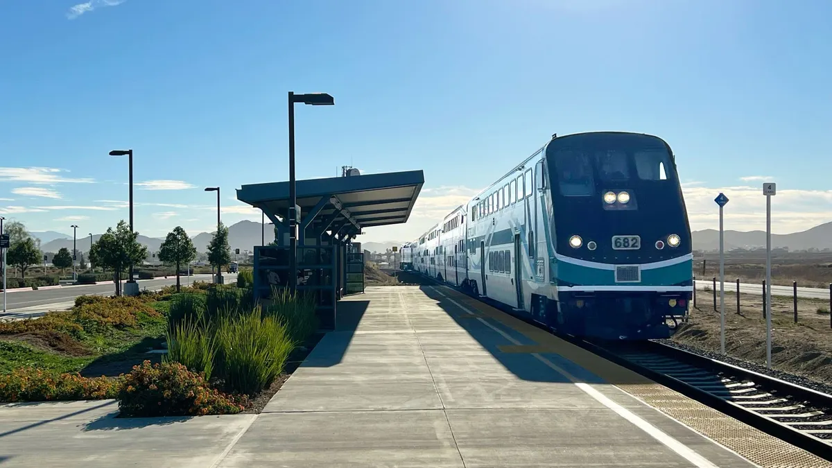 A commuter train sits at a suburban rail platform.