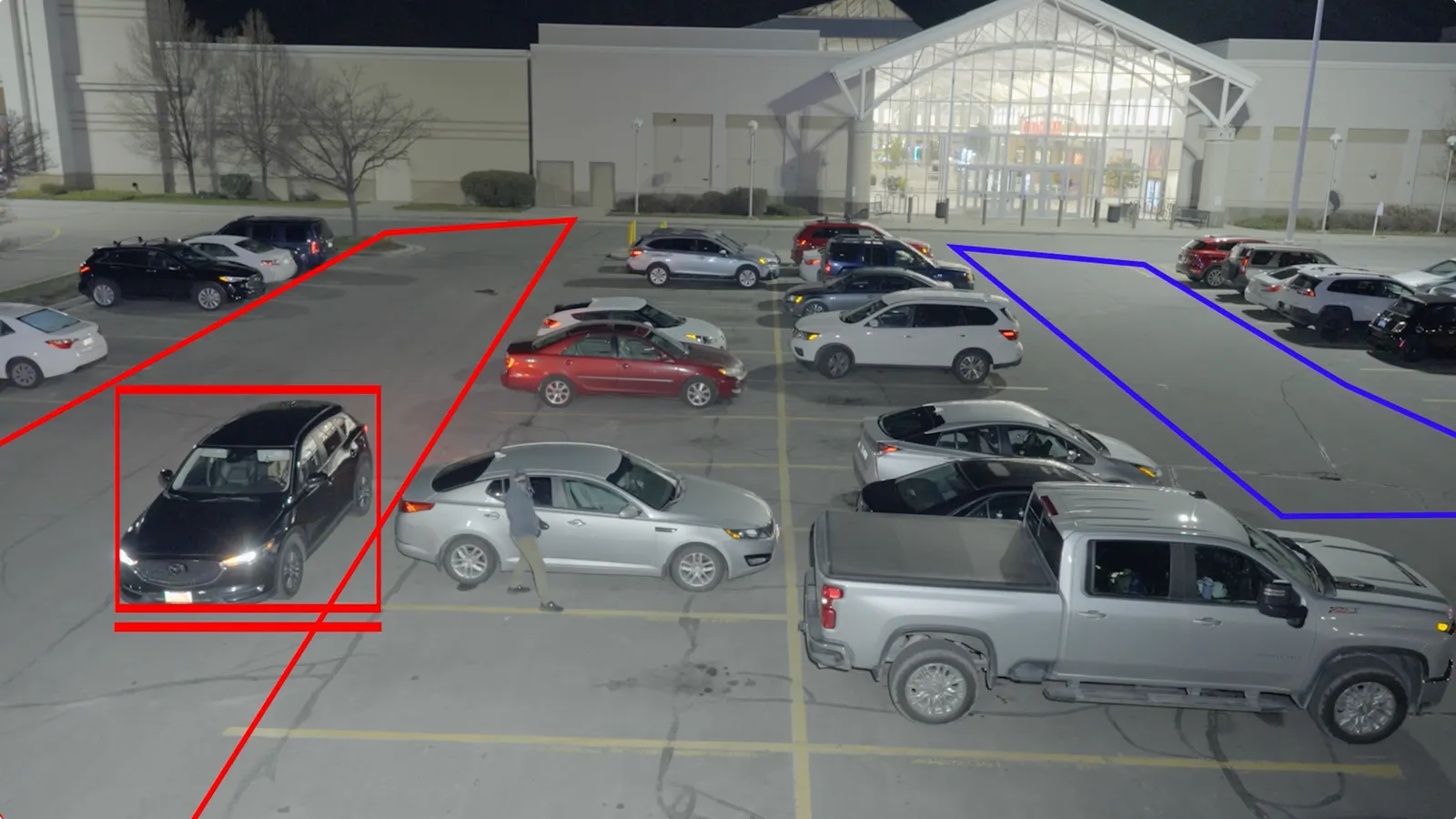 A photo of a parking lot at night, with some areas of the lot outlined in artificially added rectangles.