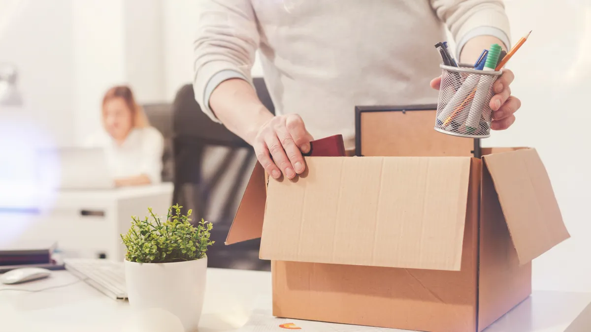 Fired man packing his stuff in a box as he cleaning his workplace before leaving the office