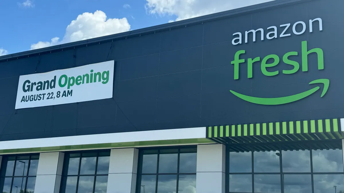 Exterior of Amazon Fresh store with banner reading "Grand Opening August 22, 8 AM"