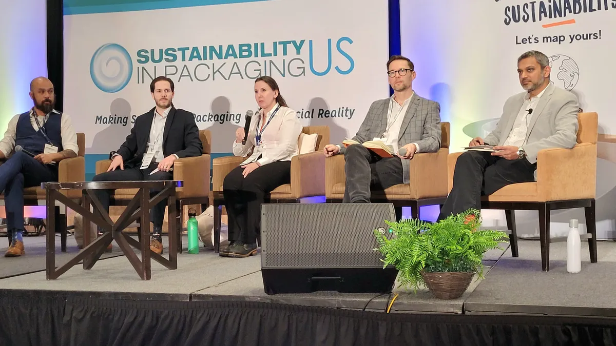 Five panelists on a stage at a conference discuss sustainability in packaging.