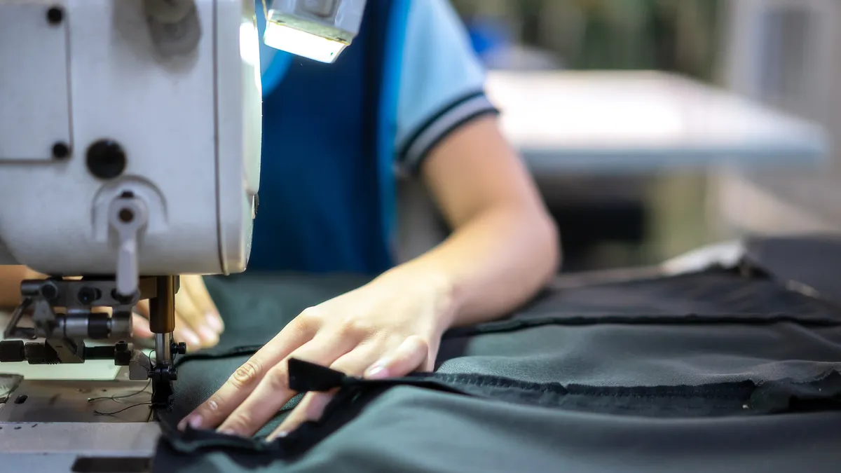 Hands of young girl using sewing machine in workshop.