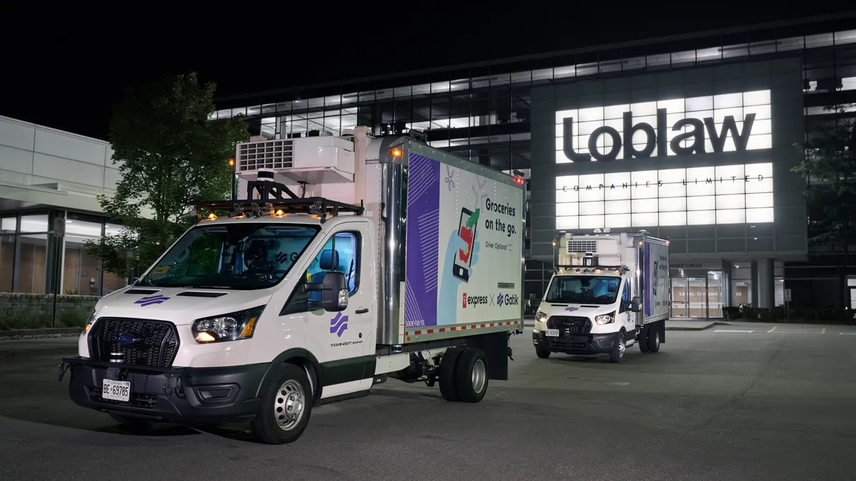 Autonomous trucks are shown in a lot at night.