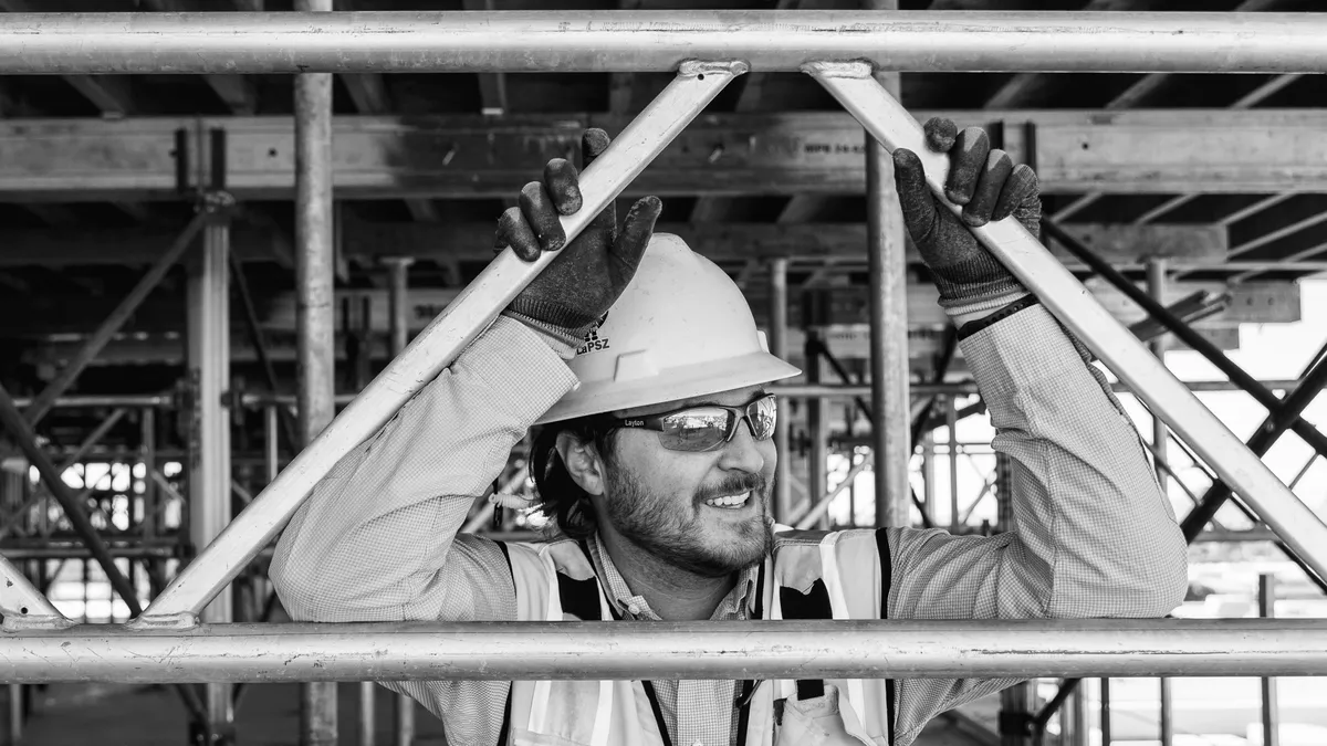 Black and white image of a man in construction hard hat smiling.