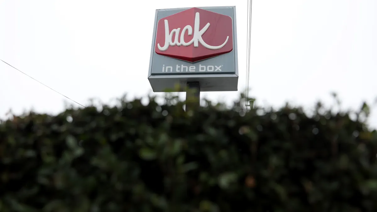 A Jack in the Box sign looms ominously from behind a hedge.