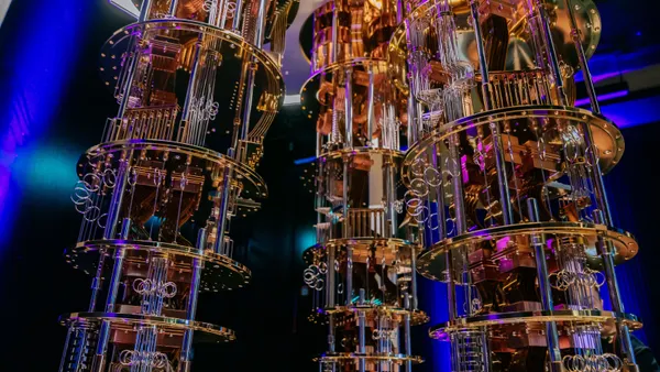 Three orange-and-black chandelier-like objects are seen against a black and blue background