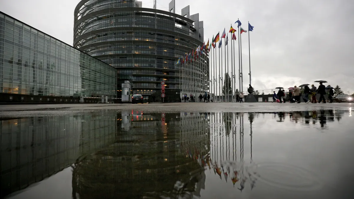 The European Parliament building is pictured with flags waving outside.