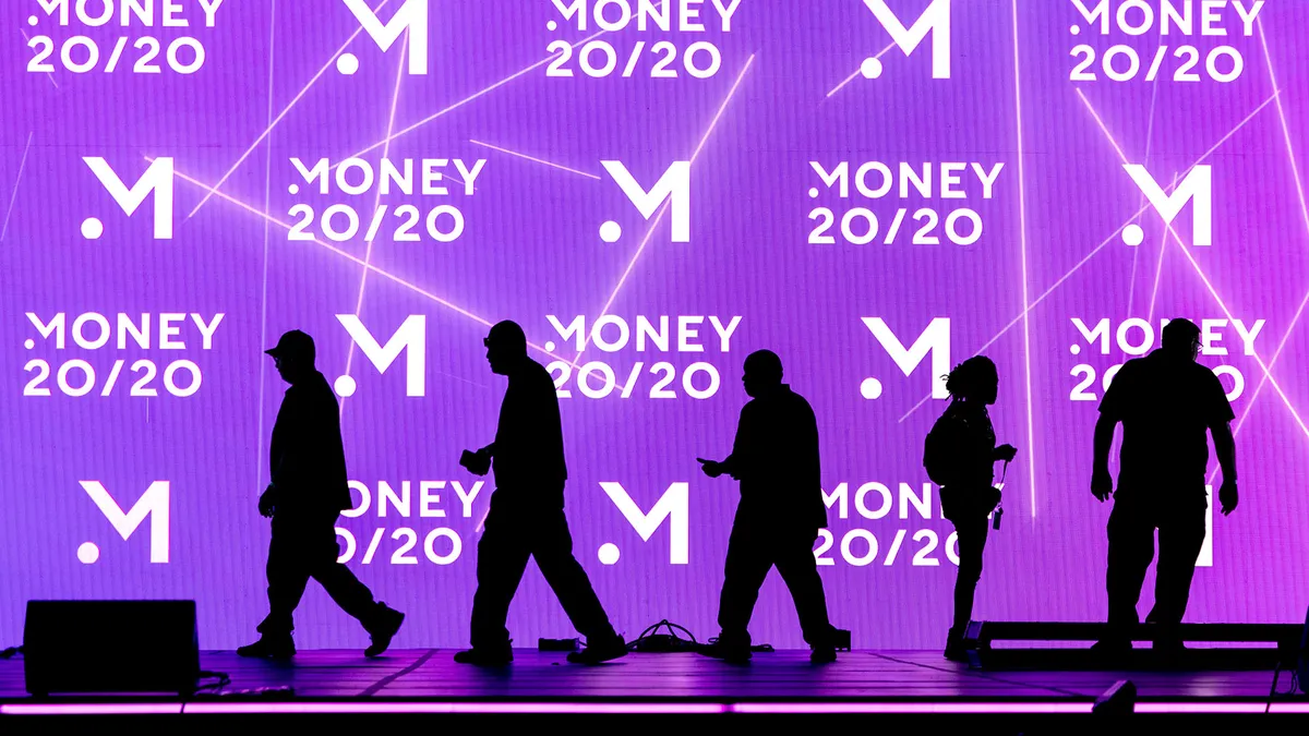 People stand in front of an illuminated stage at Money20/20.