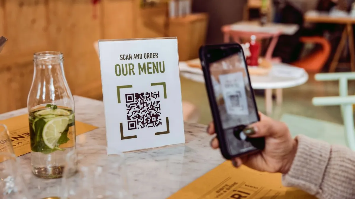 An image of a hand scanning a QR code in a restaurant.