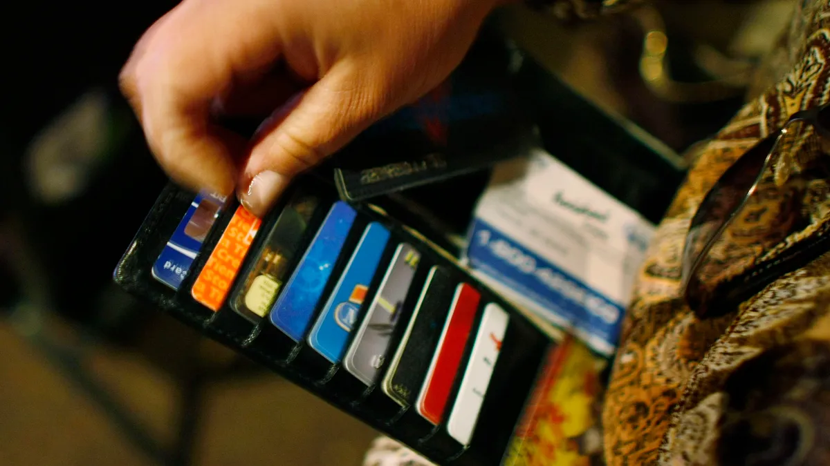 A person displays their open wallet and cards