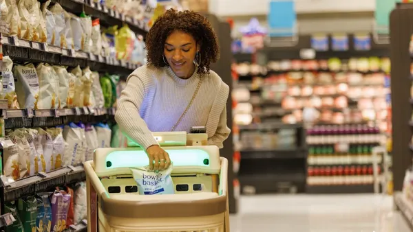 A person in a grocery store putting items in a smart cart.