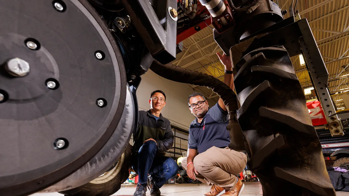 Two men look stand near a wheeled robot