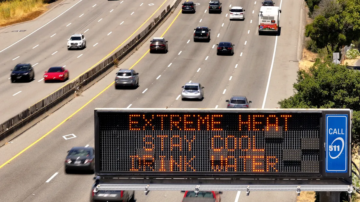 A billboard over a California highway reads "Extreme Heat Stay Cool Drink Water"