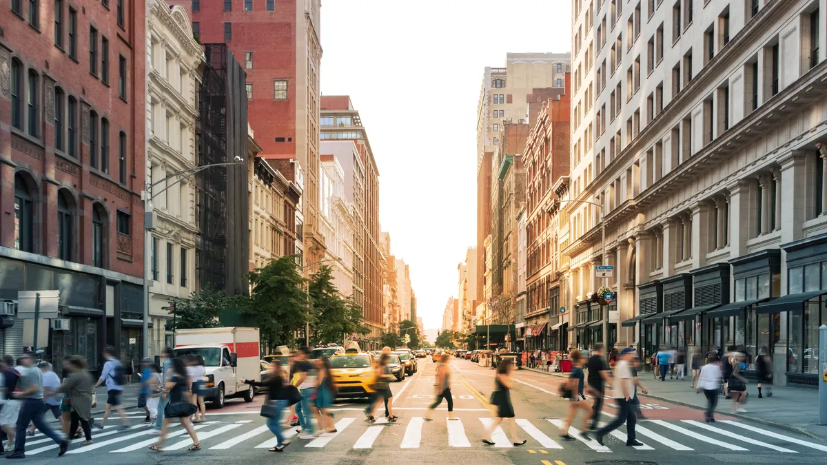 Crowds of people walking through a busy crosswalk at the intersection of 23rd Street and Fifth Avenue in Midtown Manhattan, New York City..