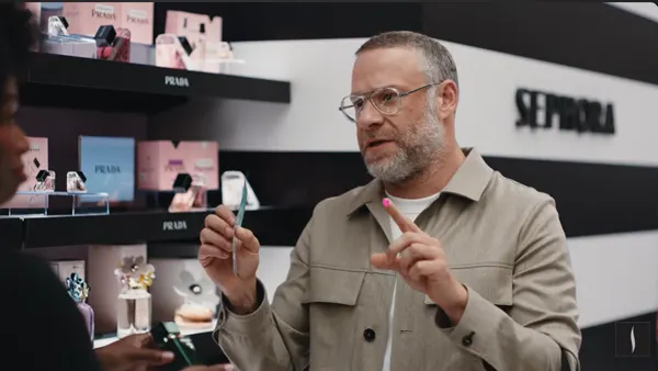 Actor Seth Rogen, wearing a taupe overshirt, shows a pimple patch stuck to his left pointer finger while standing in a Sephora store.