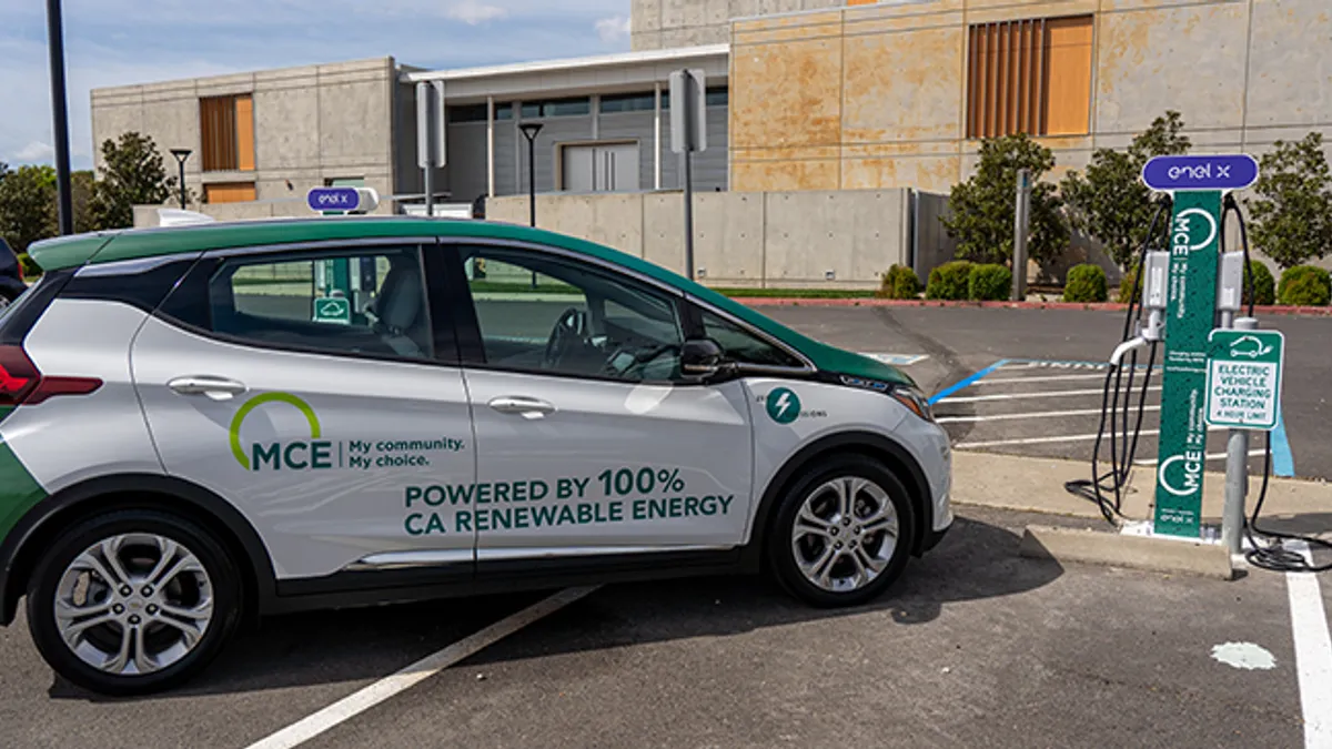 A green and white electric car parked next to a charging station