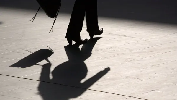 A person walks across a floor carrying a handbag.