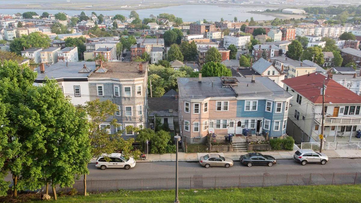 Aerial image of multifamily buildings lining the streets. Behind the homes is a large body of water.