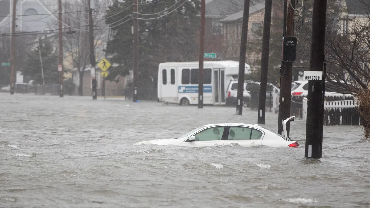 A car is submerged in water on a street flooded from a storm