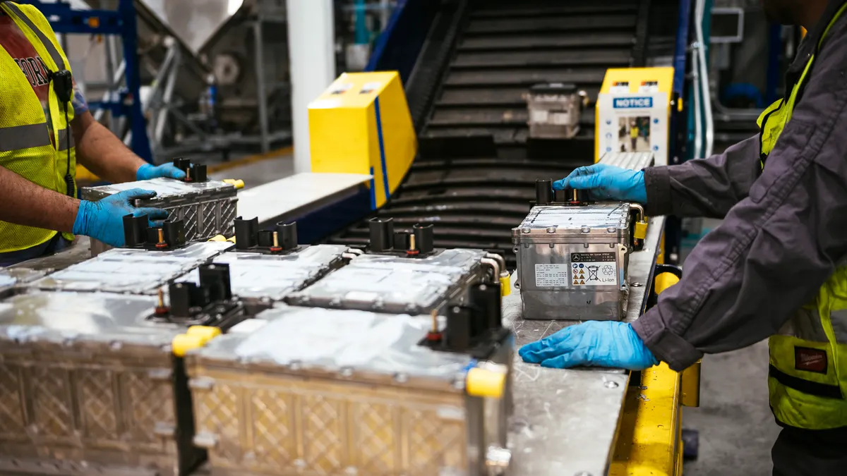 hands of workers sort large batteries on a conveyor