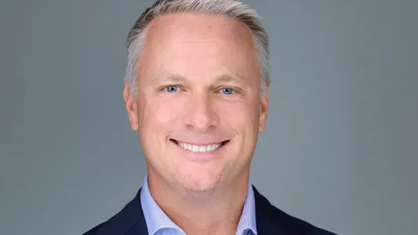 An image of a person wearing a suit and smiling.