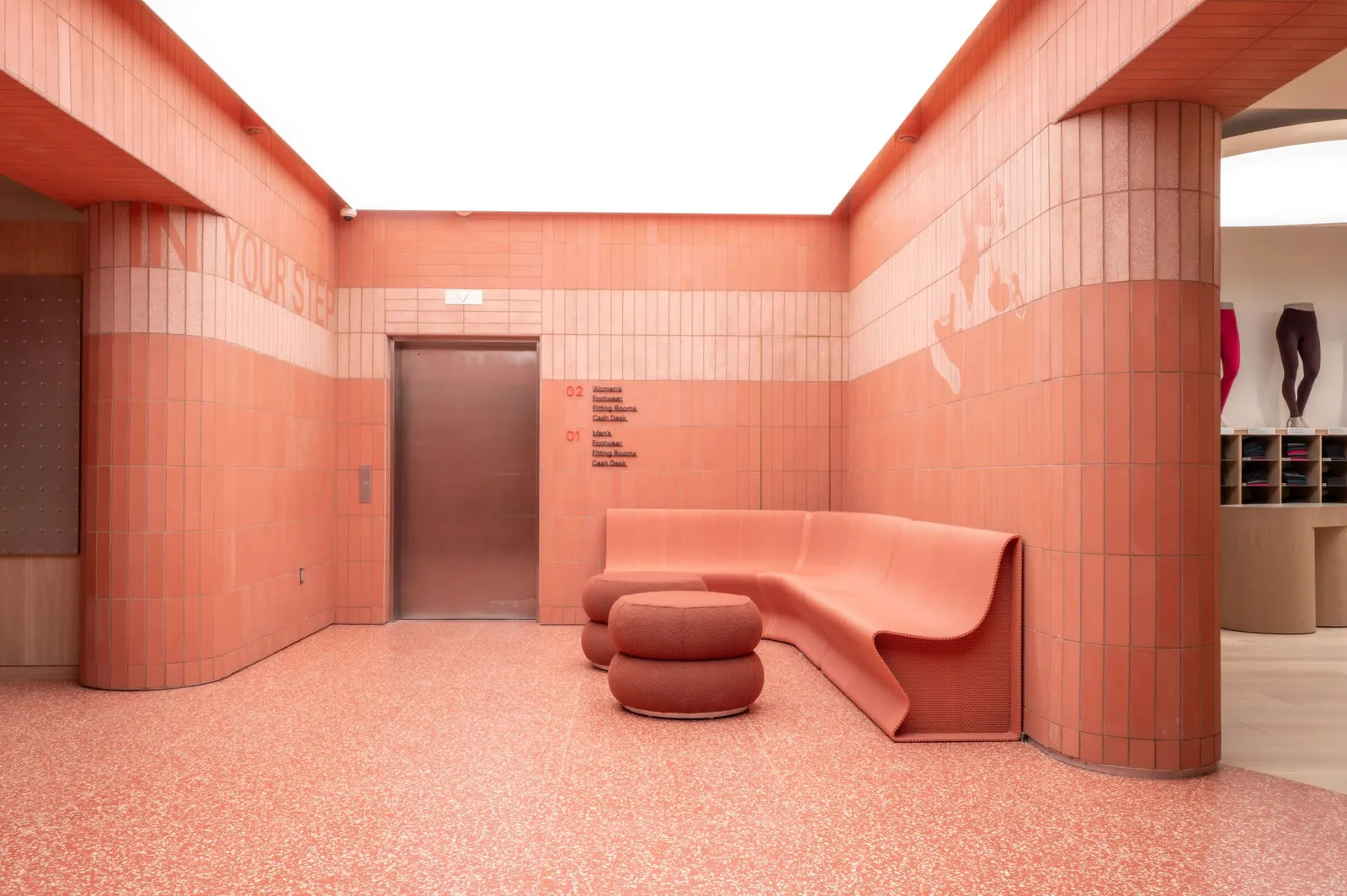 A red bench and ottoman in a hallway near elevators in Lululemon&#x27;s SoHo store.