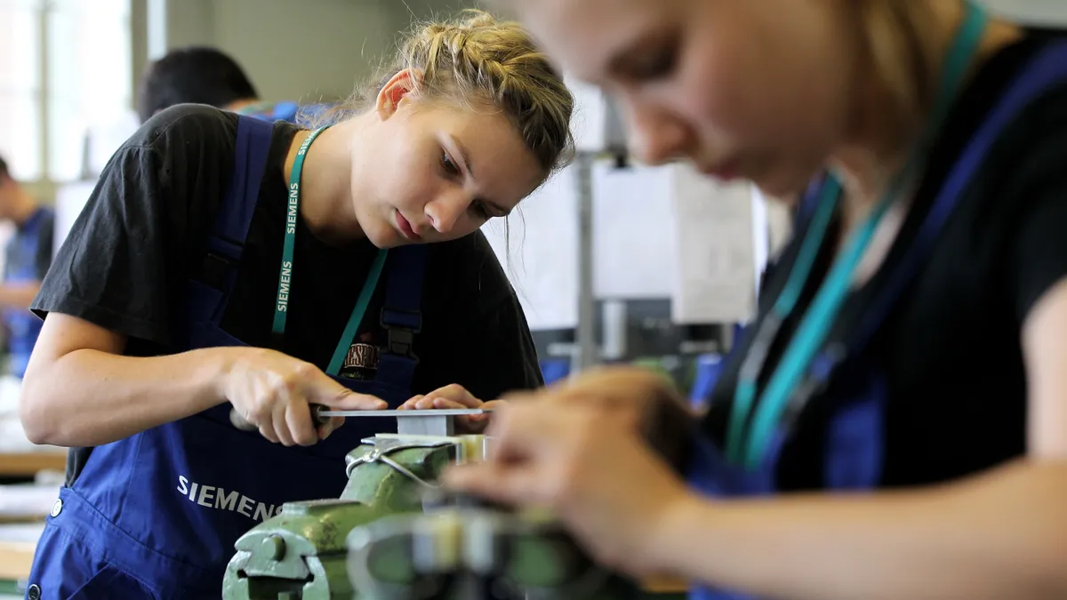 Female mechanical engineering trainees learn the basics of precision filing at a training center.