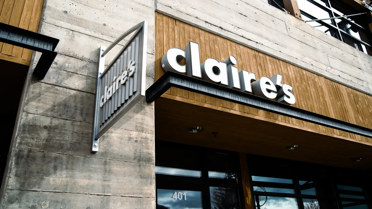 The name "claire's" in lowercase block letters adorns the gray, corrugated-metal side as well as the slatted-wood front of a storefront overhang.