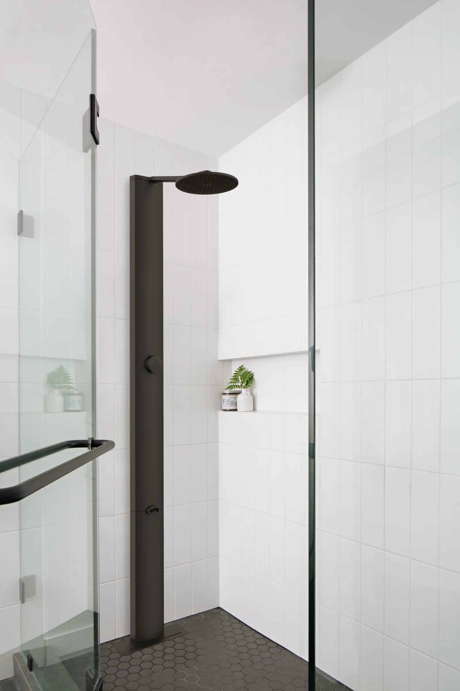 A shower with a black showerhead.