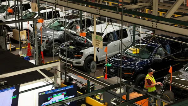 Pickup trucks are lined up within a factory to be assembled.