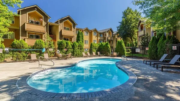 Three story apartments with a pool in the foreground