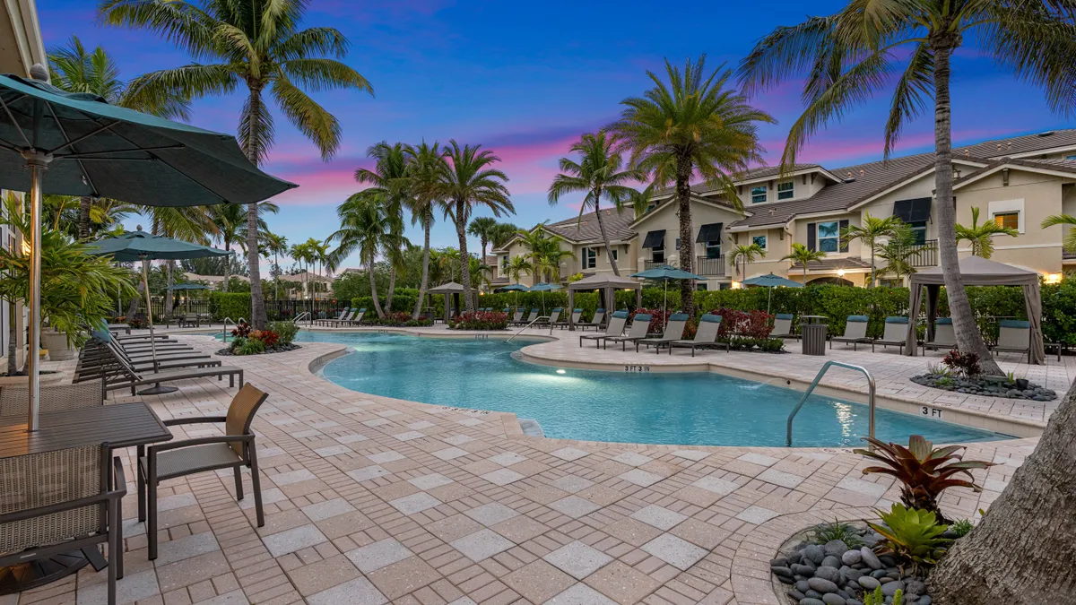 A pool surrounded by palm tress and apartments