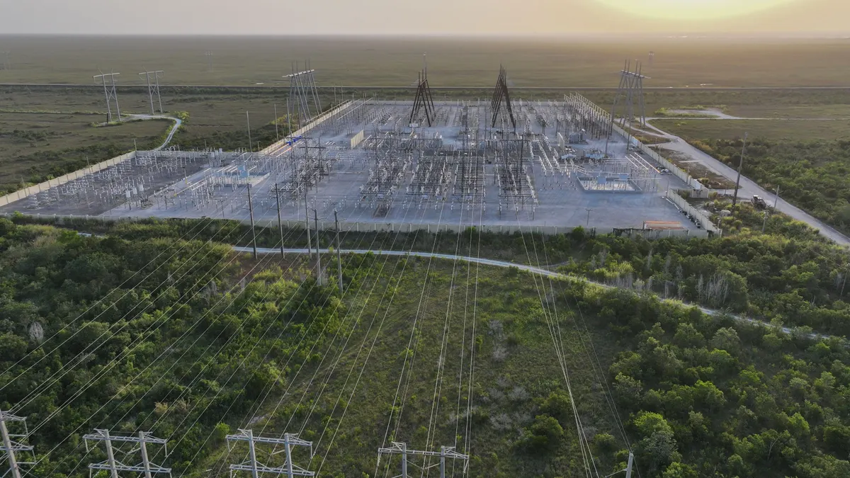 An electric substation with power lines in a grassy area.