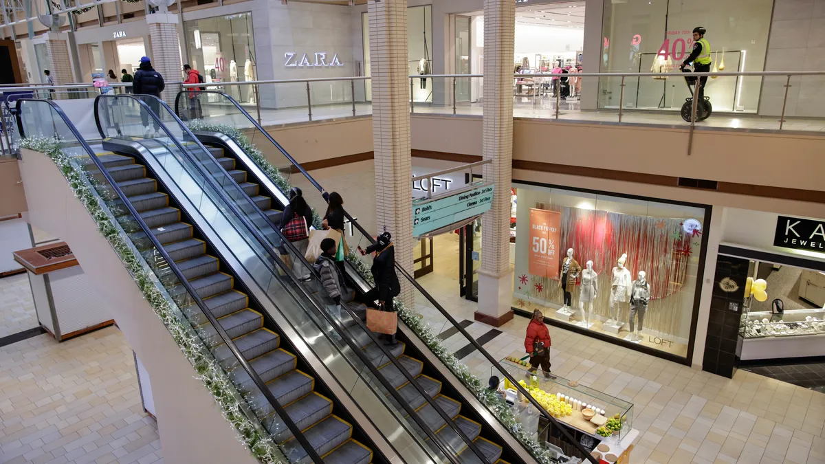 A handful of people using the escalator at an indoor mall