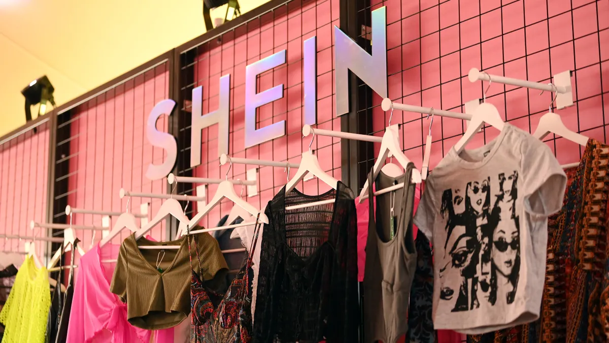 The Shein logo is displayed on a store wall above racks of clothing.