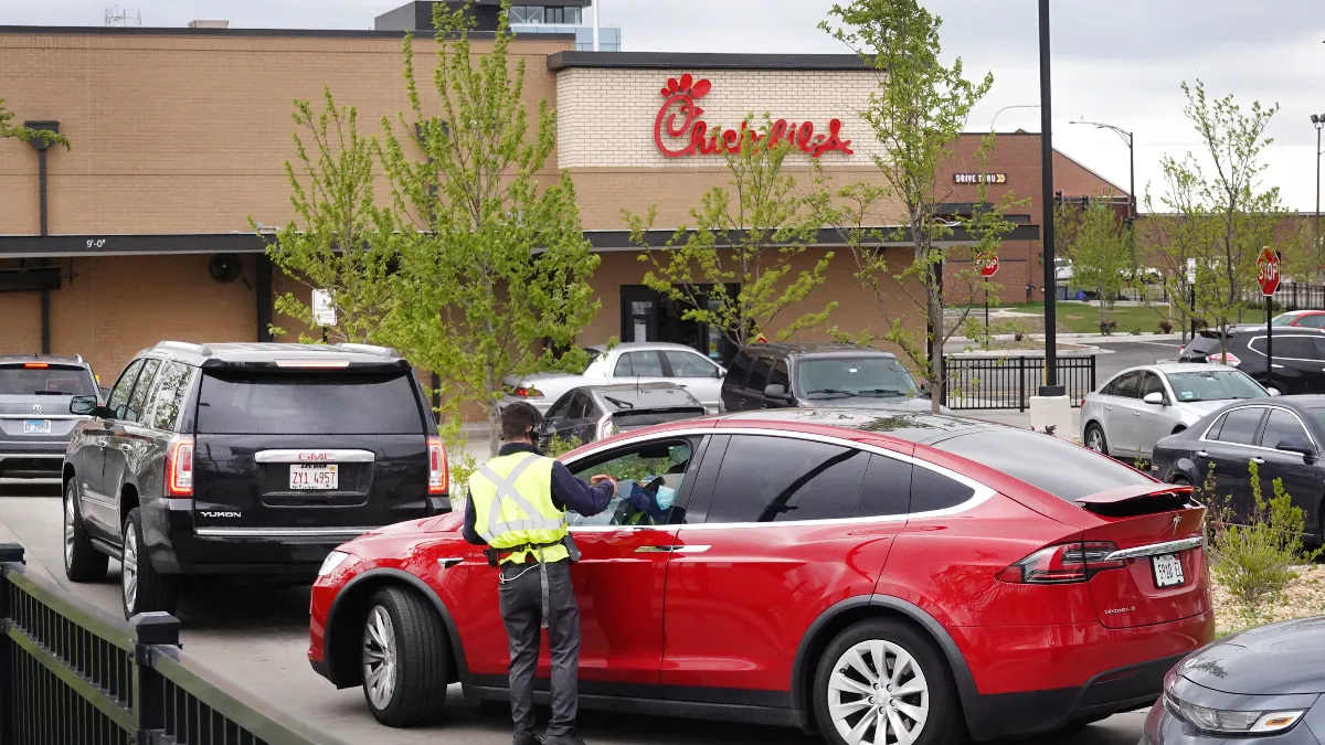 A worker takes orders from customers in the drive-thru lane at a Chick-fil-A restaurant.